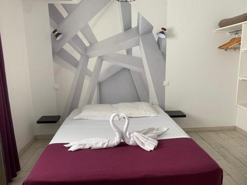 two white swans sitting on a bed in a room at Auberge des toqués in Pégomas