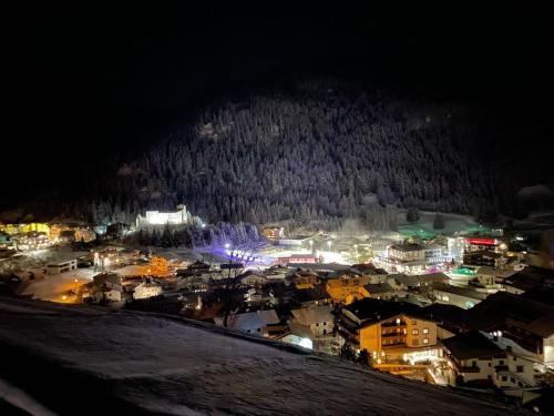 a city lit up at night with a snow covered mountain at Berghoamat Nauders in Nauders