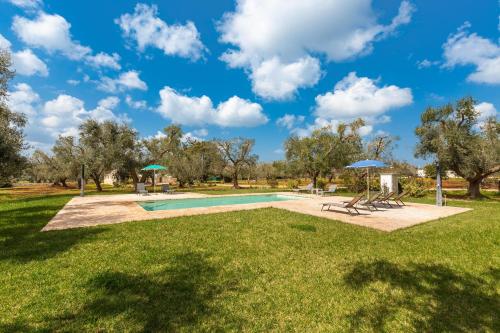 einen Pool mit Stühlen und Sonnenschirmen in einem Park in der Unterkunft Trullo Melograno by Perle di Puglia in San Michele Salentino