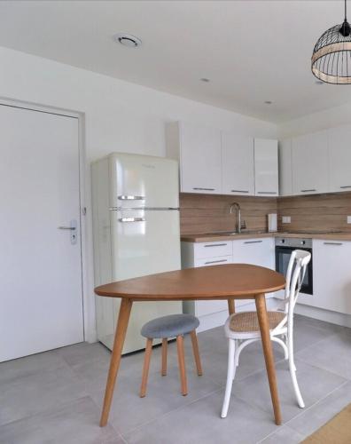 La cuisine est équipée d'une table, de deux chaises et d'un réfrigérateur. dans l'établissement Les Mimosas - T2 Ground Floor Apartment - Villeurbanne, à Villeurbanne