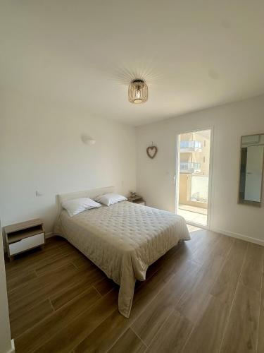 une chambre blanche avec un lit et un parquet dans l'établissement Beau 2 pièces neuf 3 personnes, à LʼÎle-Rousse