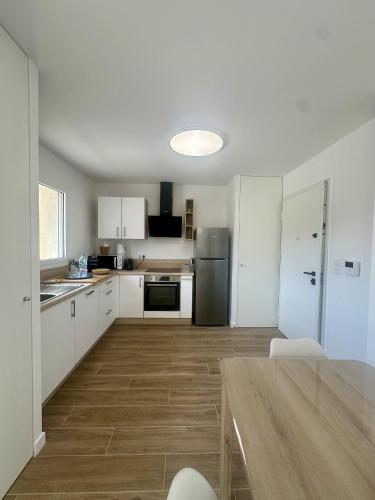 une cuisine avec des armoires blanches et un plancher en bois dans l'établissement Beau 2 pièces neuf 3 personnes, à LʼÎle-Rousse