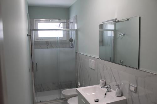 a white bathroom with a shower and a sink at Casa Marina 44 in Marina di Ragusa