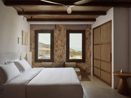 a bedroom with a large bed and two windows at Anemelia Hotel Mykonos in Elia Beach