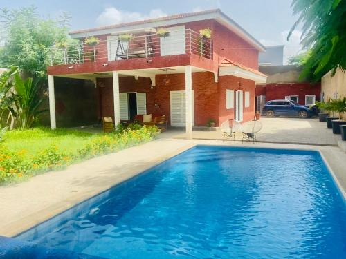 a house with a swimming pool in front of a house at Villa Madibso in Mbour