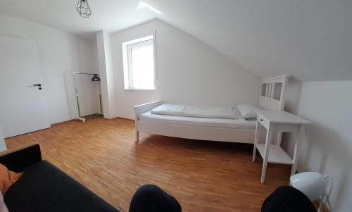 a white room with a bed and a desk at Ferienwohnung Ahornweg in Ihrlerstein