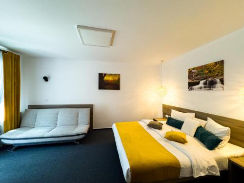 a bedroom with a large bed and a couch at Pensiunea Bradului in Colibiţa
