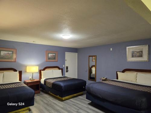 a bedroom with two beds and a blue wall at Rodeway Inn & Suites Blythe I-10 in Blythe