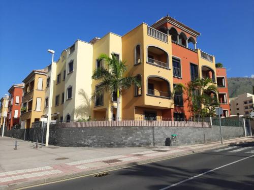 a building with palm trees in front of a street at Paula Pool Apartment Adeje in Adeje
