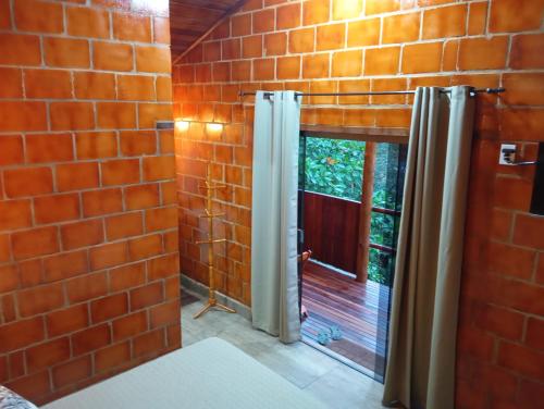 a bathroom with a brick wall and a window at Chalés Pedacim du Céu in Bueno Brandão