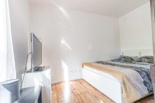 une chambre blanche avec un lit et une télévision à écran plat dans l'établissement Studio Disneyland Paris, à Montévrain