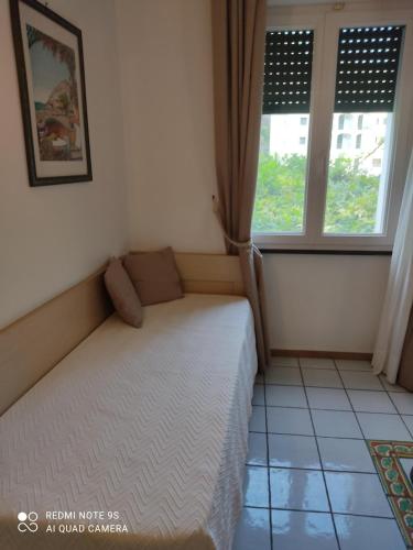 a small bedroom with a bed and two windows at Pietra di Luna residence in Maiori