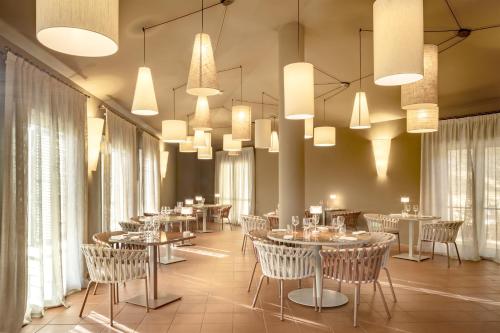 a dining room with tables and chairs and chandeliers at Veridia Resort Sardinia, a member of Radisson Individuals in Chia