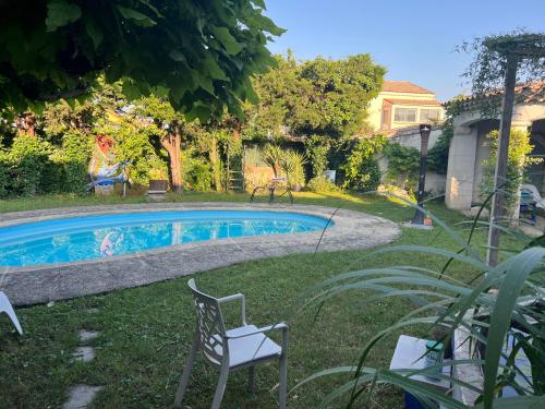 a swimming pool in a yard with two chairs and a house at Chambre Zen King Size in Pierrelatte