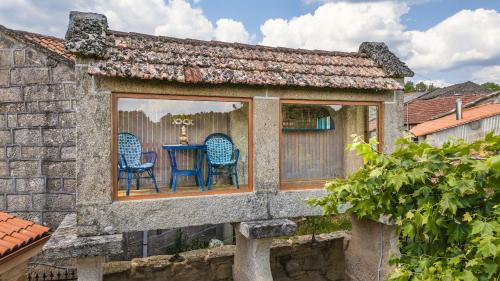 a house with two blue chairs in a window at Alojamiento Pazos in Cea