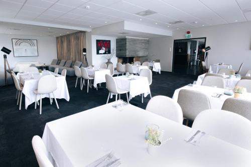a dining room with white tables and white chairs at Live Lofoten Hotel in Stamsund