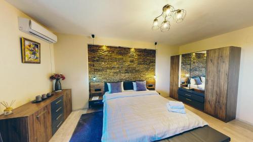 a bedroom with a bed and a brick wall at JANINE GARDEN in Braşov