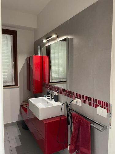 a bathroom with a white sink and red cabinets at Casa di Sveva in Marotta