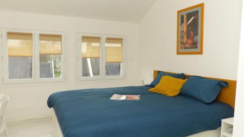 ein Schlafzimmer mit einem blauen Bett mit zwei Fenstern in der Unterkunft Charmante maison de vacances - Le Bono in Le Bono
