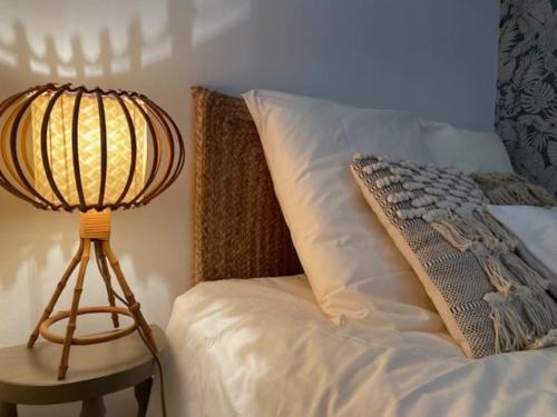 une lampe assise à côté d'un lit avec un oreiller dans l'établissement Calussine maison provençale, à Pernes-les-Fontaines