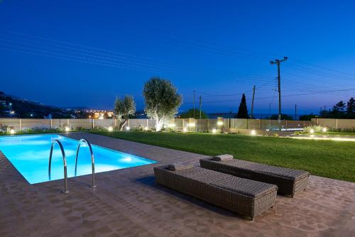 a swimming pool at night with a couch next to it at Elaia Luxury Suites Lagonisi in Lagonissi