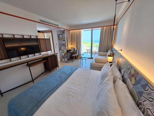 a bedroom with a large bed and a television at Folie Marine Hotel & Beach Club in Jal