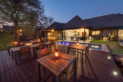 a deck with tables and chairs and a pool at Moya Safari Villa in Hoedspruit