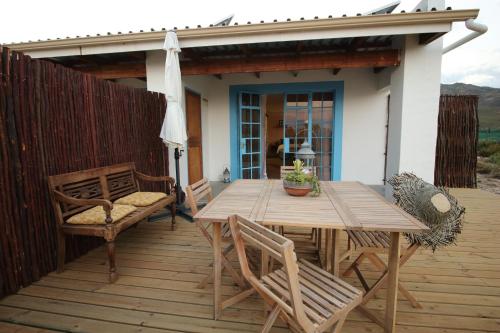 a wooden table and chairs on a wooden deck at Starry Starry Night - Route 62 in Montagu