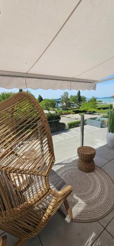 a wicker chair sitting under an umbrella on a patio at Infinity Apartman Lellemarine in Balatonlelle