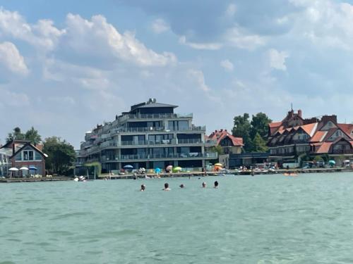 a group of people in the water in front of a building at Infinity Apartman Lellemarine in Balatonlelle