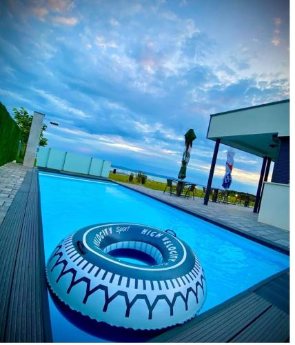 a swimming pool with a large tire on the deck at Infinity Apartman Lellemarine in Balatonlelle