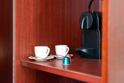 two coffee cups and saucers on a wooden shelf at The Couper Umiltà in Rome