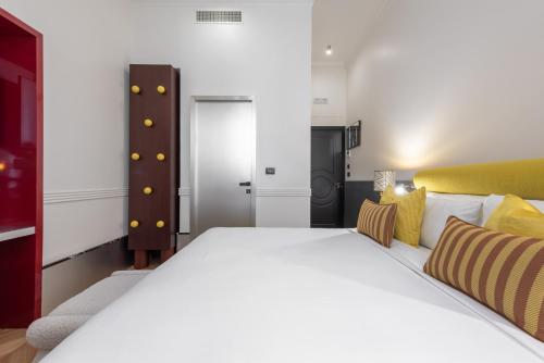 a bedroom with a large white bed with yellow accents at The Couper Umiltà in Rome