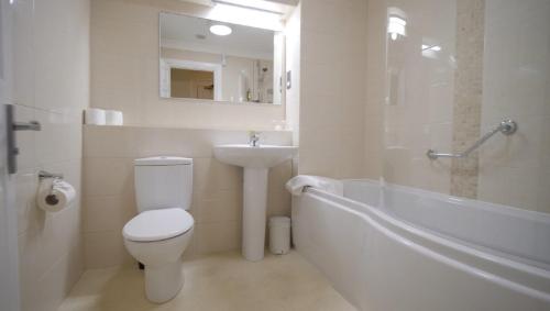 a bathroom with a toilet and a sink and a bath tub at The Osborne Apartments in Torquay