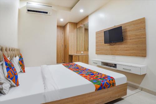 a bedroom with a bed and a flat screen tv at FabHotel Prime OM Palace in Bhopal