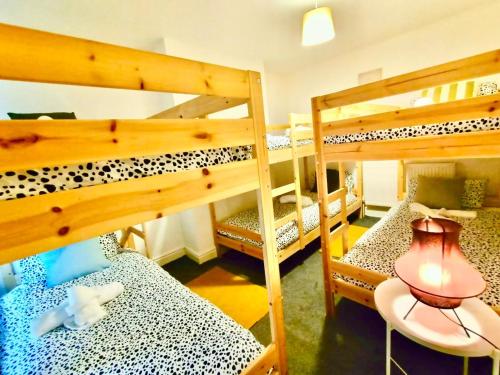 a room with three bunk beds with a table and a lamp at Liverpool 4 Bed Home Sleeps 18 Free Parking in Liverpool