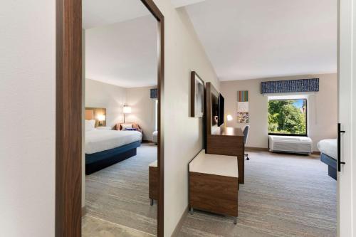 a hotel room with a bed and a mirror at Hampton Inn Milford in Milford
