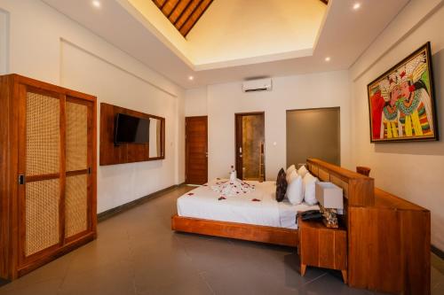 a bedroom with a bed and a tv on the wall at Alamdini Resort Ubud in Ubud