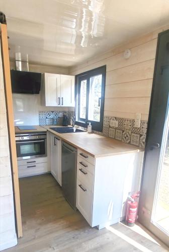 une cuisine avec des armoires blanches et un comptoir dans l'établissement Tiny House - Mas du Soleil, à Bagnols-sur-Cèze