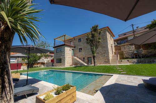 a villa with a swimming pool in front of a building at Cruzeiros Guest House, piscina, jacuzi, grupos in Tangil