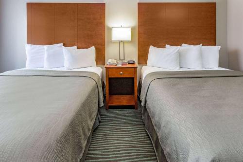 a hotel room with two beds and a table with a lamp at AmericInn by Wyndham Des Moines Airport in Des Moines