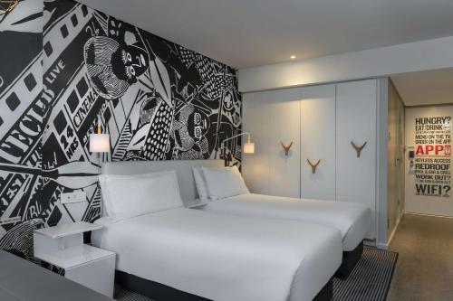 a bedroom with a white bed and a black and white wall at Radisson RED Hotel V&A Waterfront Cape Town in Cape Town