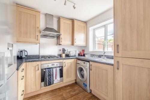a kitchen with wooden cabinets and a washer and dryer at Windsor 10 Mins - 3 Bedrooms, 2 Bathrooms House with Parking - By Tempstay in Slough