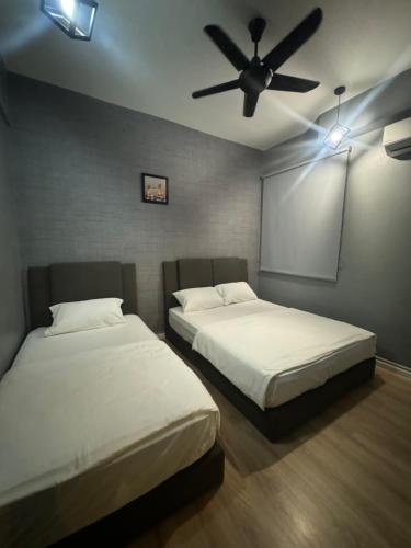 two beds in a room with a ceiling fan at The Majestic Executive Suite - Ipoh in Ipoh