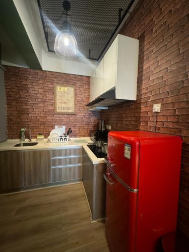 a red refrigerator in a kitchen with a brick wall at The Majestic Executive Suite - Ipoh in Ipoh