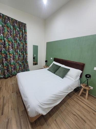 a bedroom with a large white bed with a green wall at Guest house Romana Vecchia in Monticchio