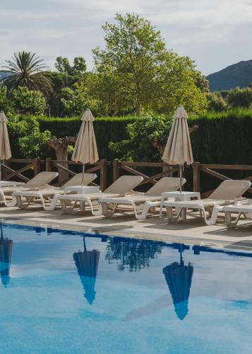 a group of chairs and umbrellas next to a swimming pool at Hotel Spa Mediterraneo Park in Roses
