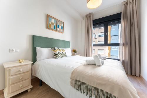 a bedroom with a large bed with a window at MalagaSuite Comfortable Home Apartments in Málaga