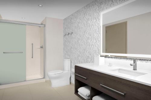 a bathroom with a sink and a toilet and a mirror at Home2 Suites By Hilton Falls Church in Falls Church