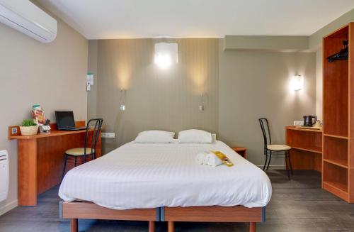 a bedroom with a large white bed with two chairs at Brit Hotel Reims La Pompelle in Reims